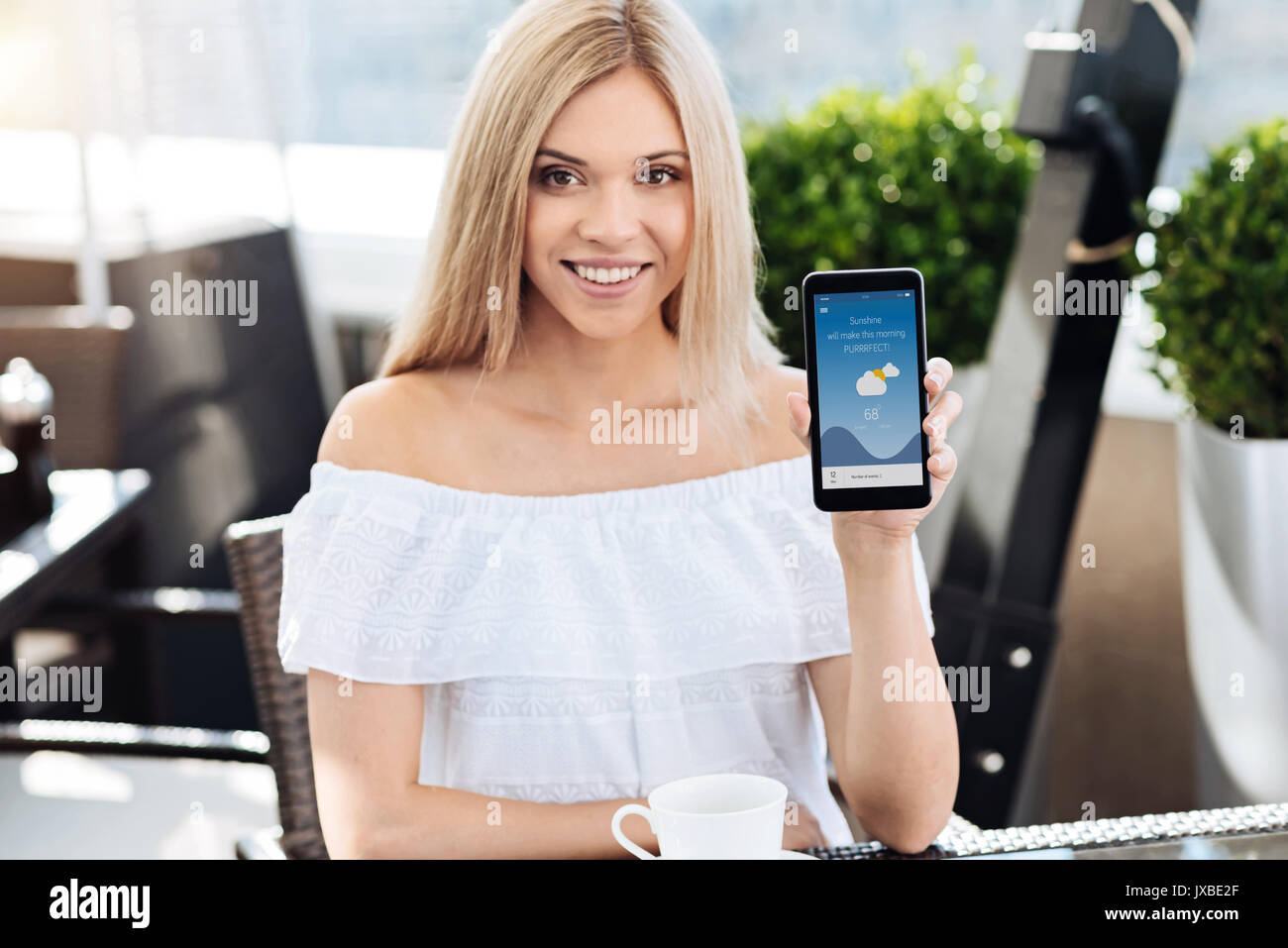 Femme blonde ravi de vous montrer son smartphone Banque D'Images