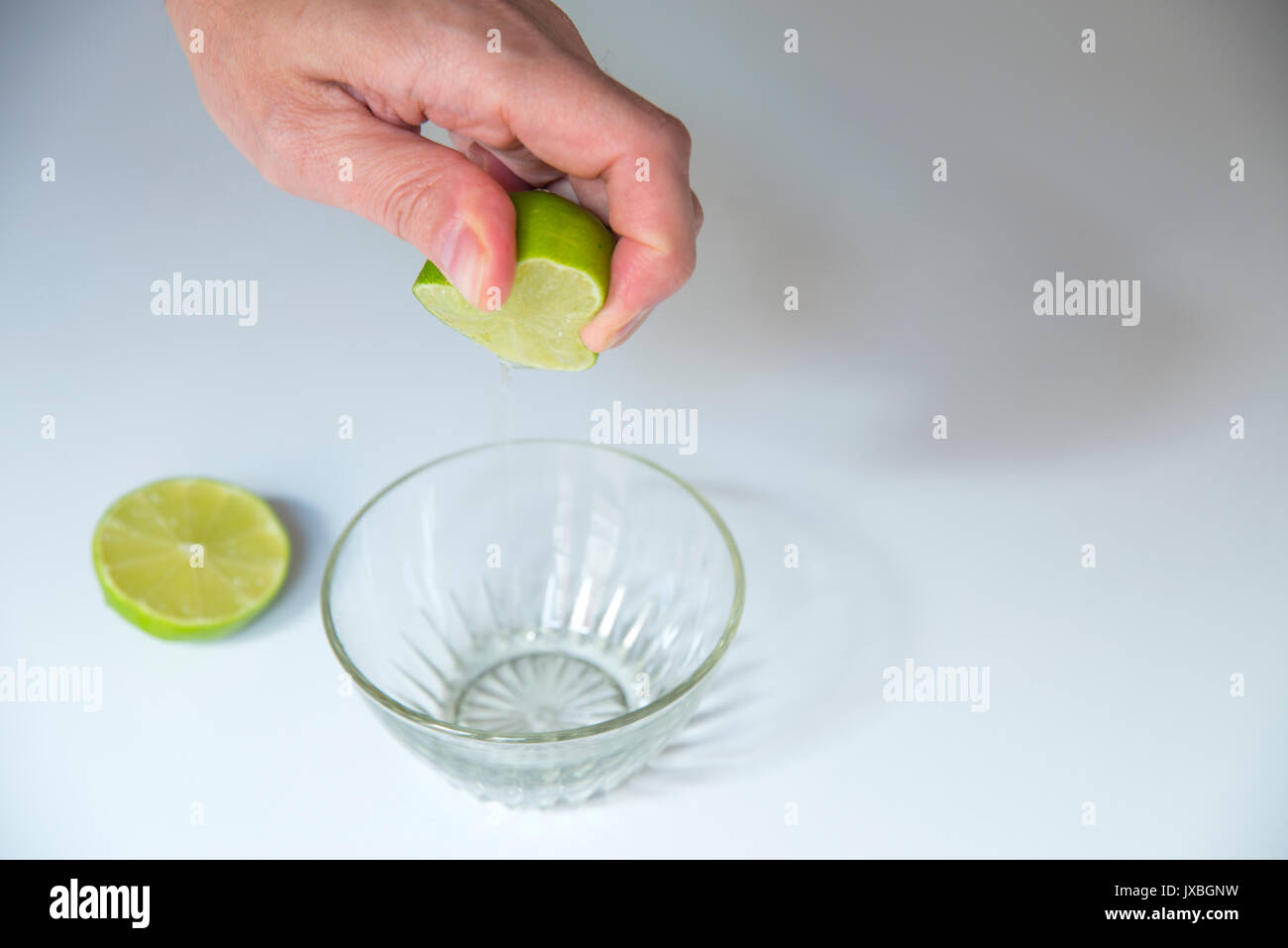 Man's hand squeezing lime demi sur un bol. Banque D'Images