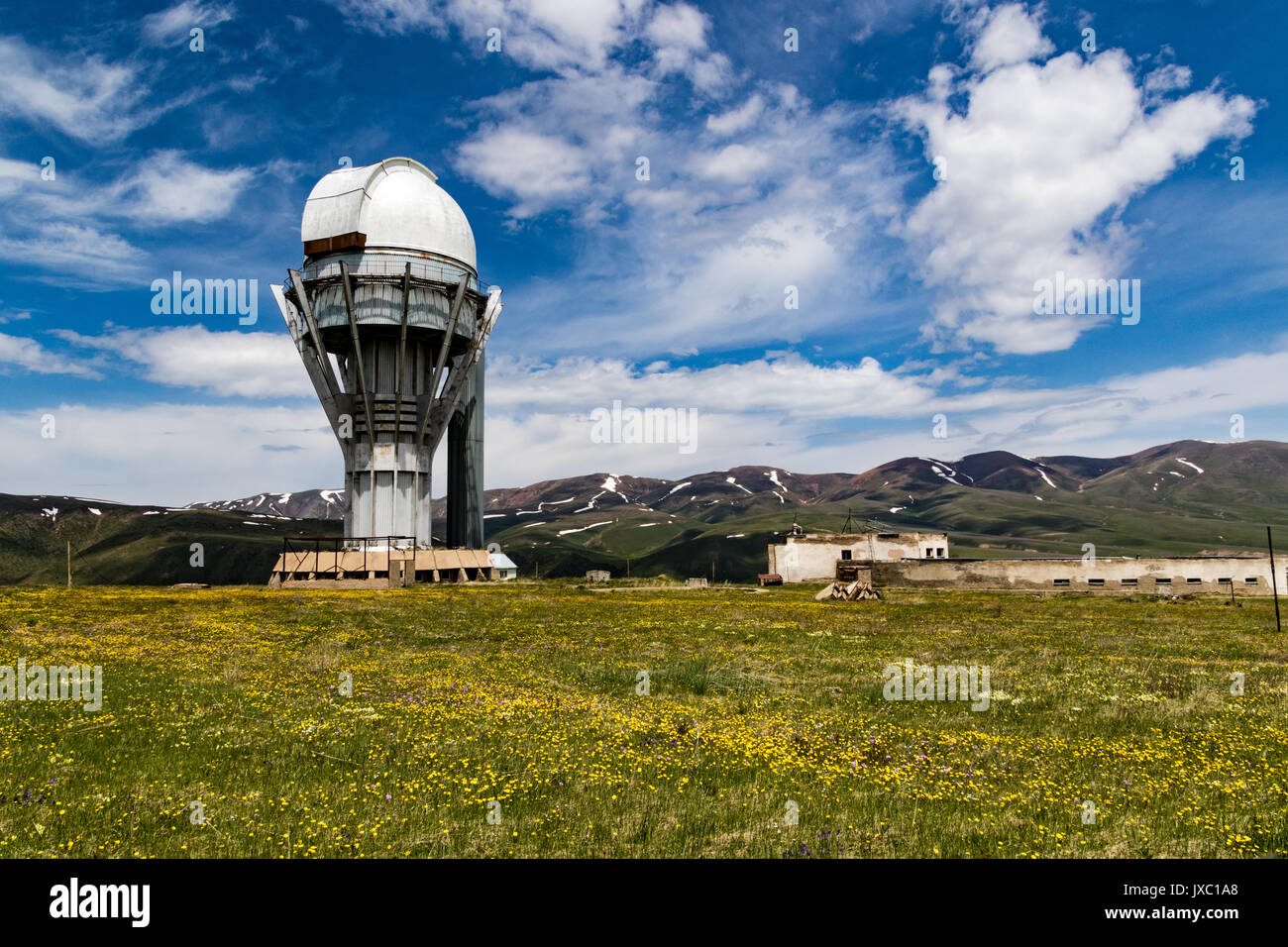 Observatoire de l'Assy-Turgen avec tour plein de montagnes et nuages derrière Banque D'Images