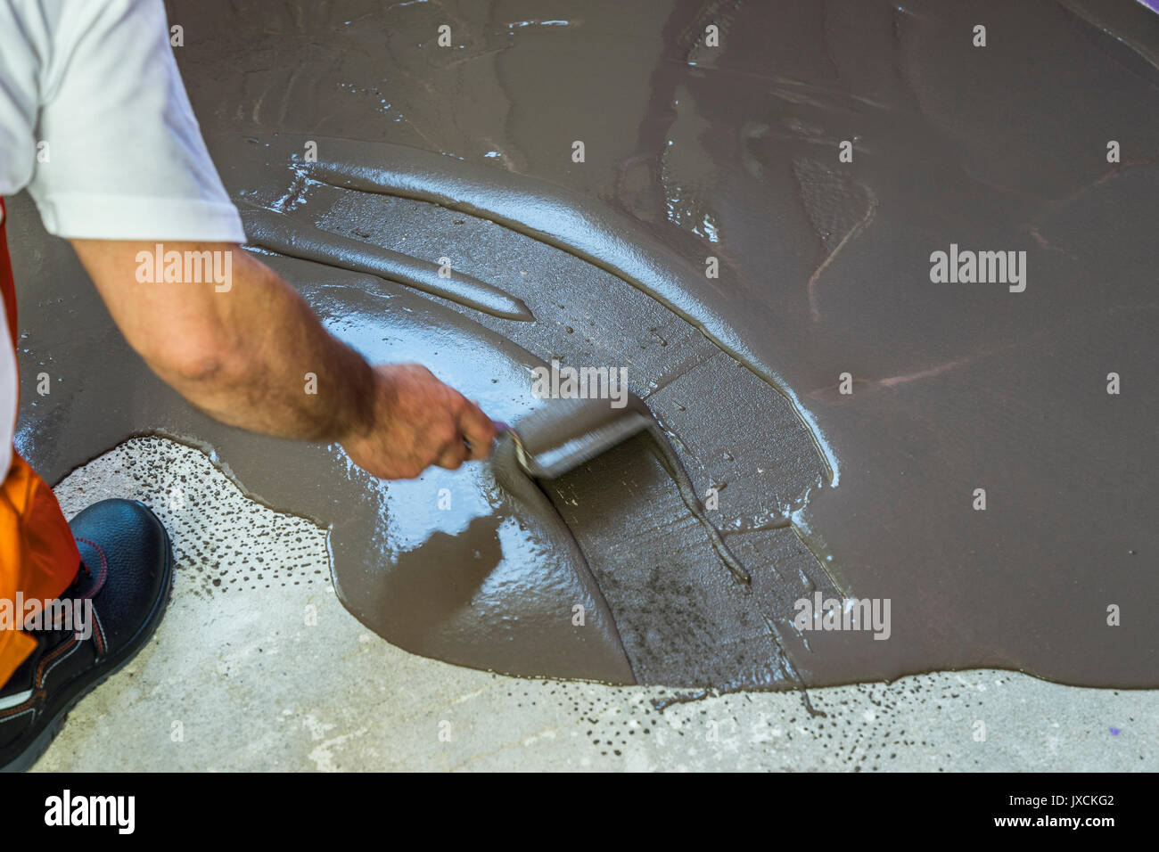 Worker met une chape d'auto-nivellement sur plancher de béton Banque D'Images