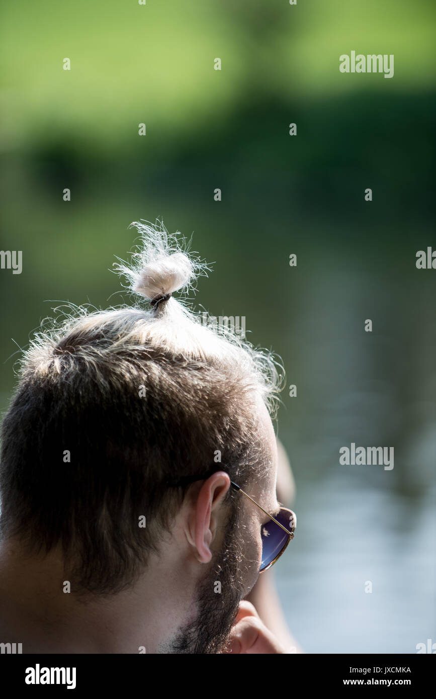 Jeune homme avec cheveux attachés sur le dessus comme un chignon. Banque D'Images