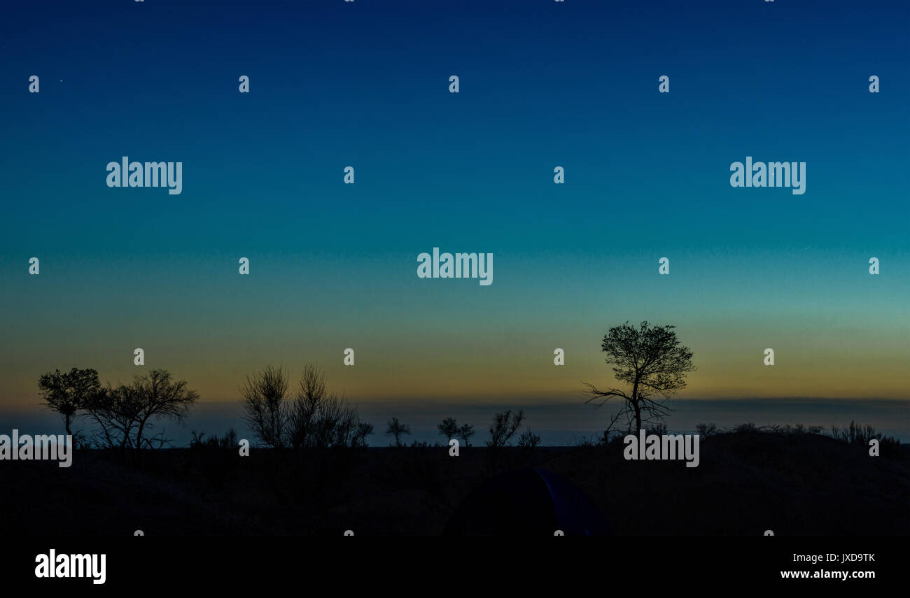 Silhouettes d'arbres sur colline avec ciel colorés sur fond de Banque D'Images