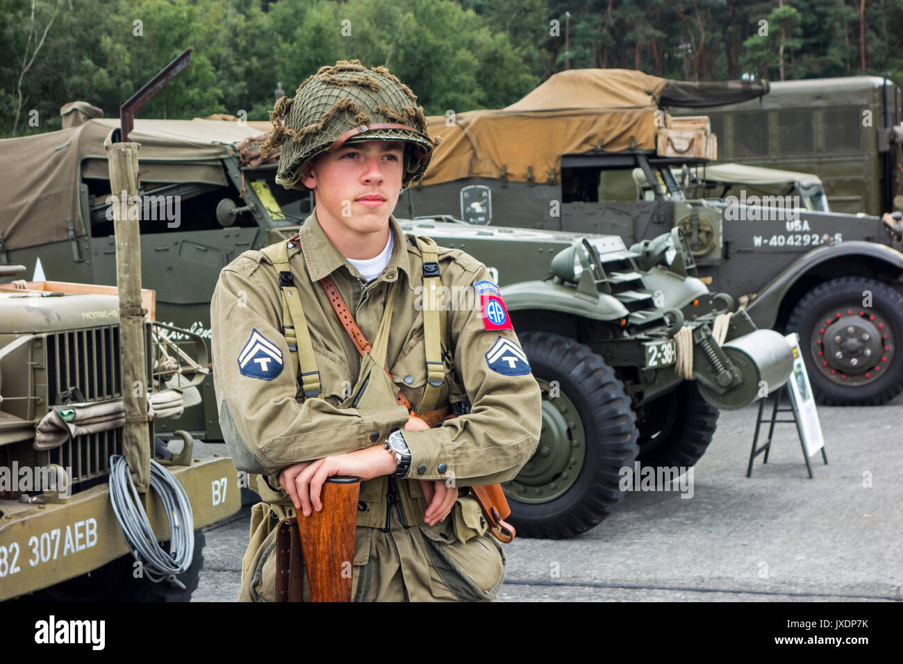 Les jeunes de la reconstitution médiévale posing in WW2 US Airborne uniforme avec grade de technicien/5e année d'un insigne à l'avant de la Seconde Guerre mondiale, deux camions américains à militaria juste Banque D'Images