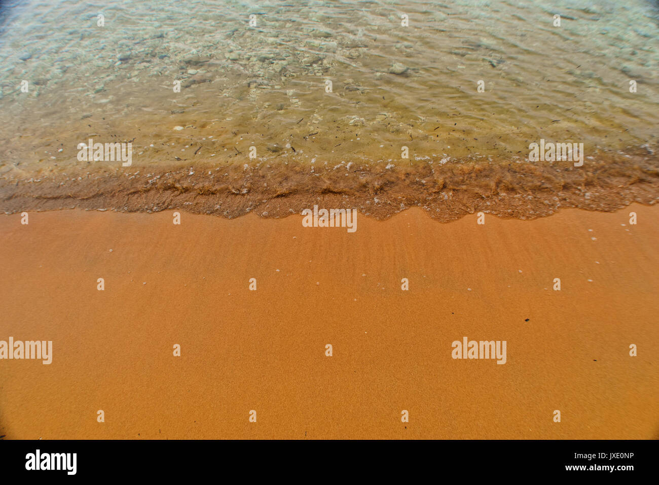 Clapotis de la mer doucement sur une plage sable orange Banque D'Images