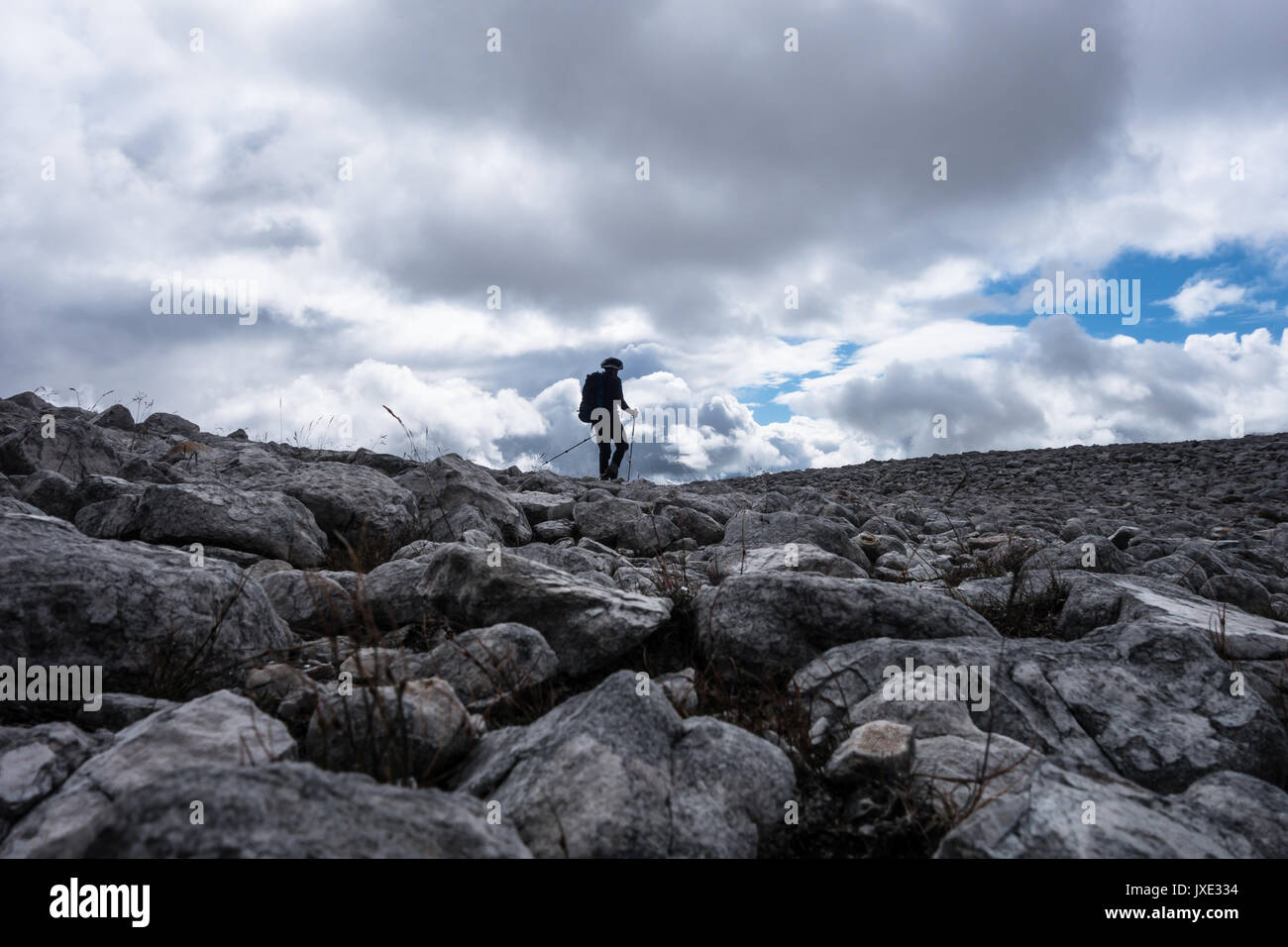 Mountain walker en silhouette contre le ciel nuageux sur rock domaine menant jusqu'au-dessus d'un cairn Munro dans les Highlands écossais Banque D'Images