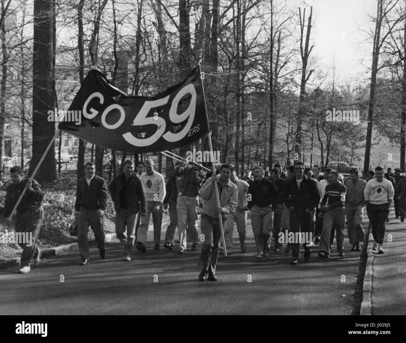 La vie étudiante, classe jour franc cliché pris au cours d'une journée de classe, procession Groupe d'étudiants titulaires d'un rendez-vous 59ers banner sont à pied par l'entremise du campus, 1955. Banque D'Images