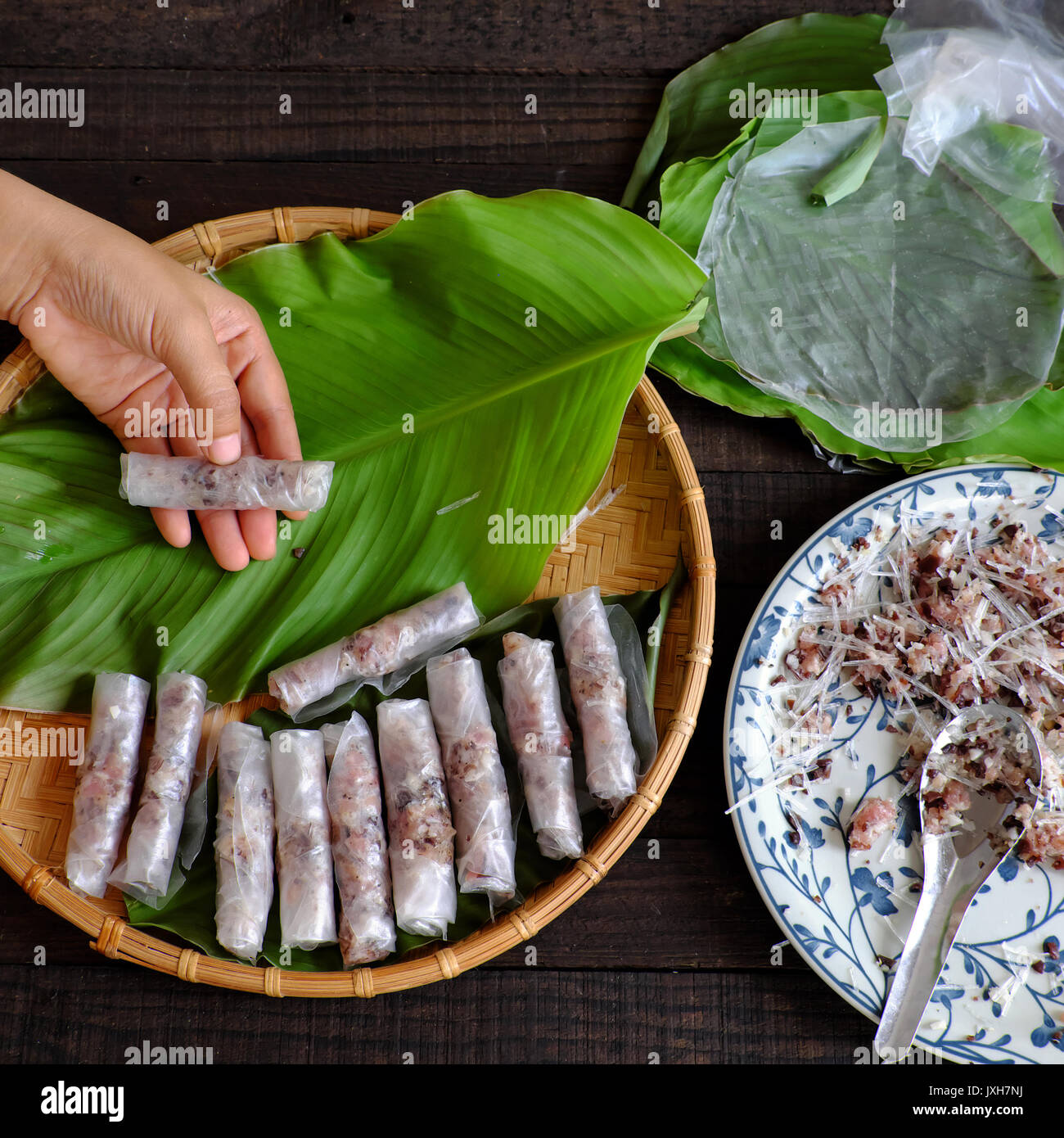 Femme faisant des rouleaux de printemps ou cha gio à la maison, une cuisine maison farce de viande et de l'enrubanneuse en papier de riz, de part le matériel roulant aux œufs de vietnamiens sur vert Banque D'Images