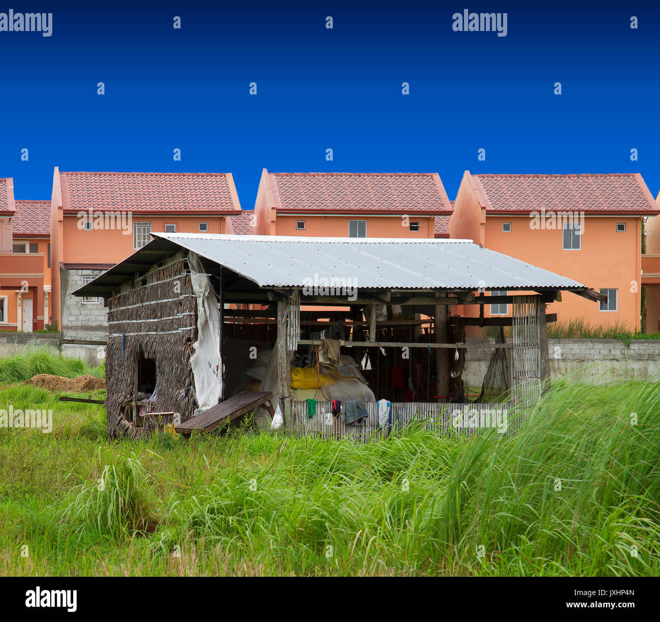 Lone nipa hut en contraste avec l'augmentation des maisons de lotissement. Banque D'Images