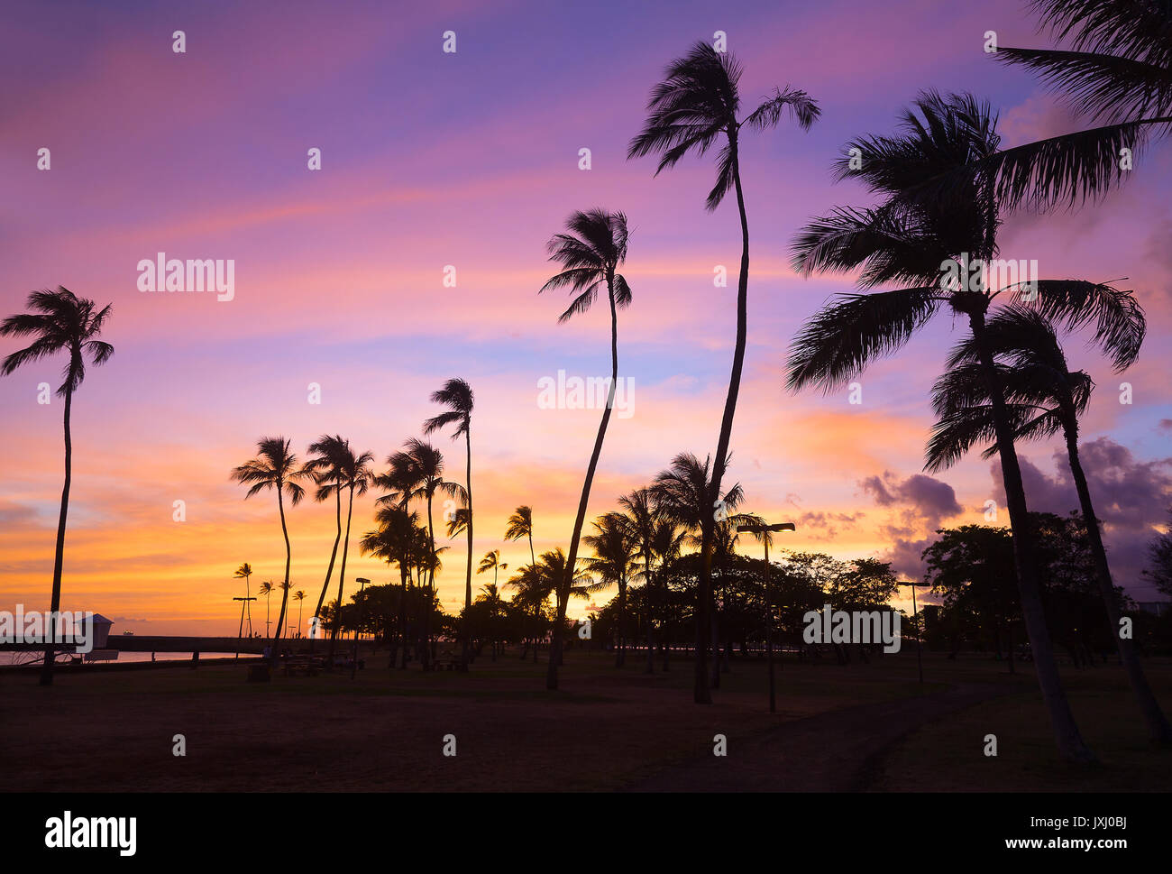 De soleil colorés à Waikiki beach à Hawaii, USA. Tropical Beach au coucher du soleil avec pal heights contre le ciel. Banque D'Images