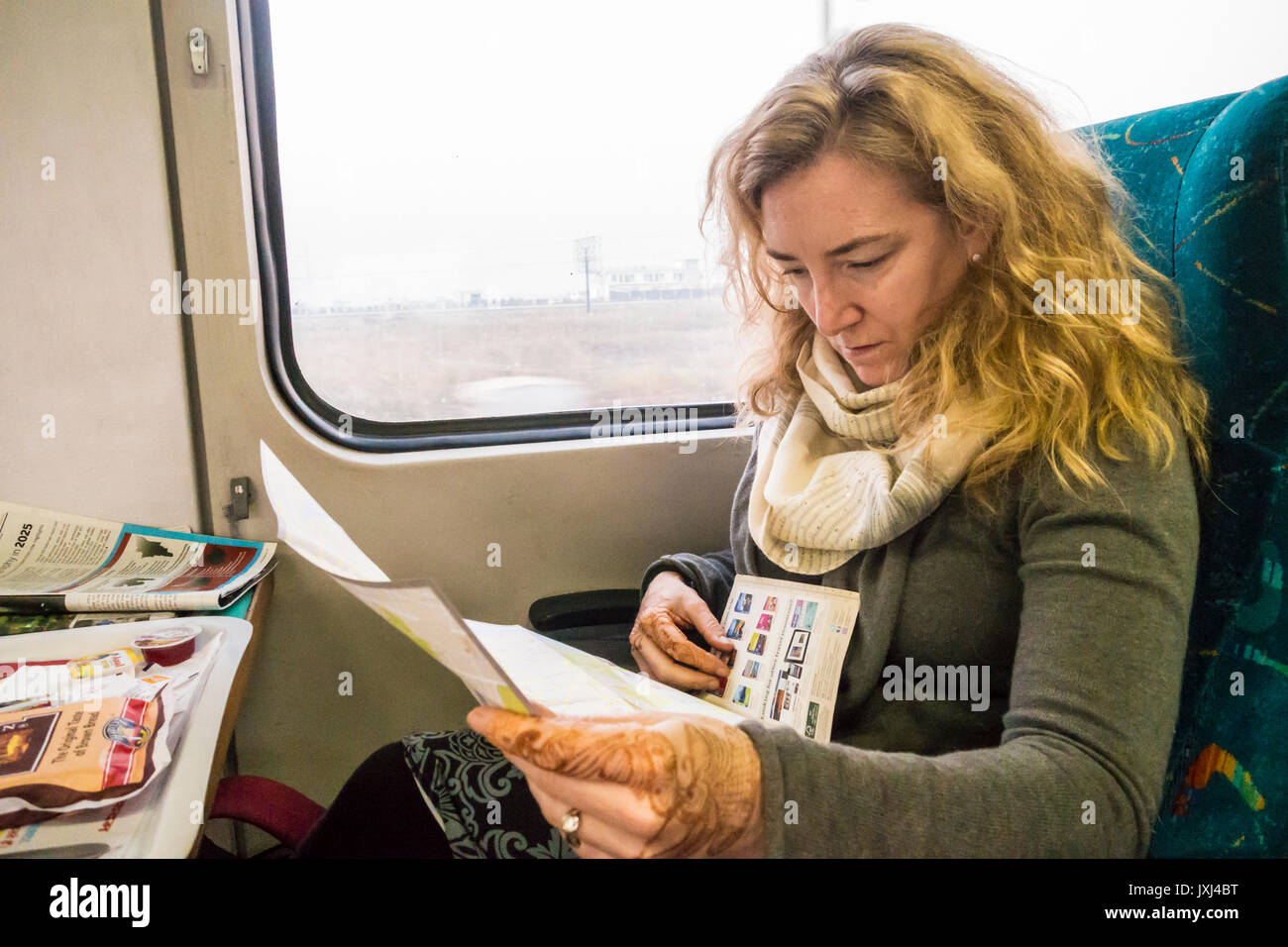 Une femme dans un train entre Delhi et Agra Inde étudier l'information de voyage et les cartes. Banque D'Images