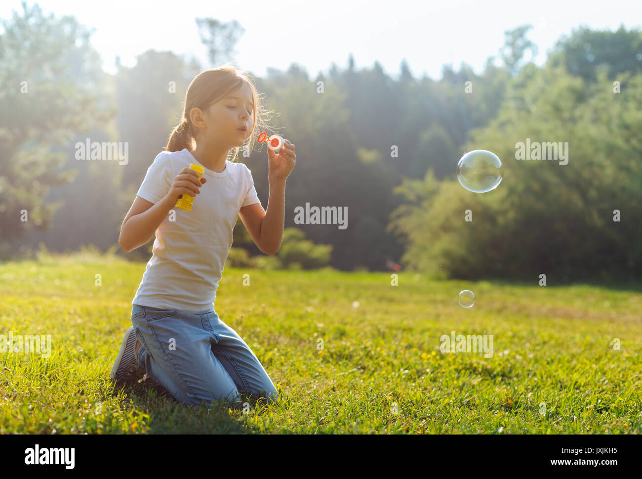 Little girl blowing bubbles dans le pré Banque D'Images