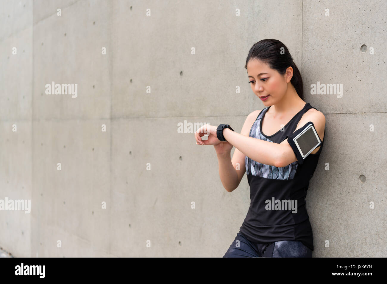 Belle femme athlète professionnel portant des smart watch en utilisant app sport notice de fréquence cardiaque personnel et prêt pour la formation en cours d'exécution sur gris ba Banque D'Images