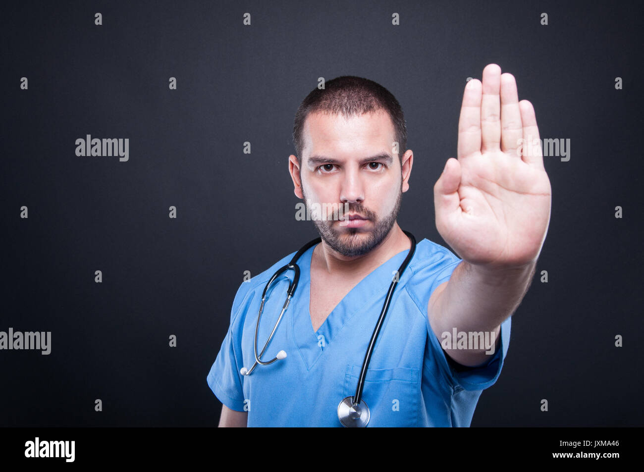 Portrait de l'homme médecin montrant le geste d'arrêt sur fond noir avec copie espace zone publicitaire Banque D'Images