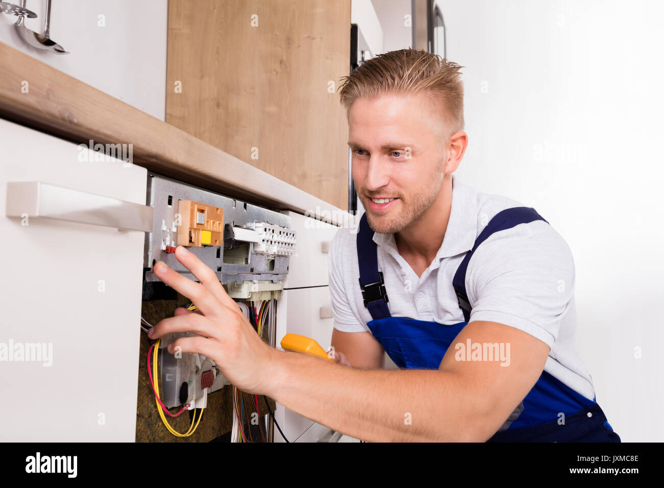 Jeune mâle fixation technicien numérique avec lave-vaisselle Banque D'Images