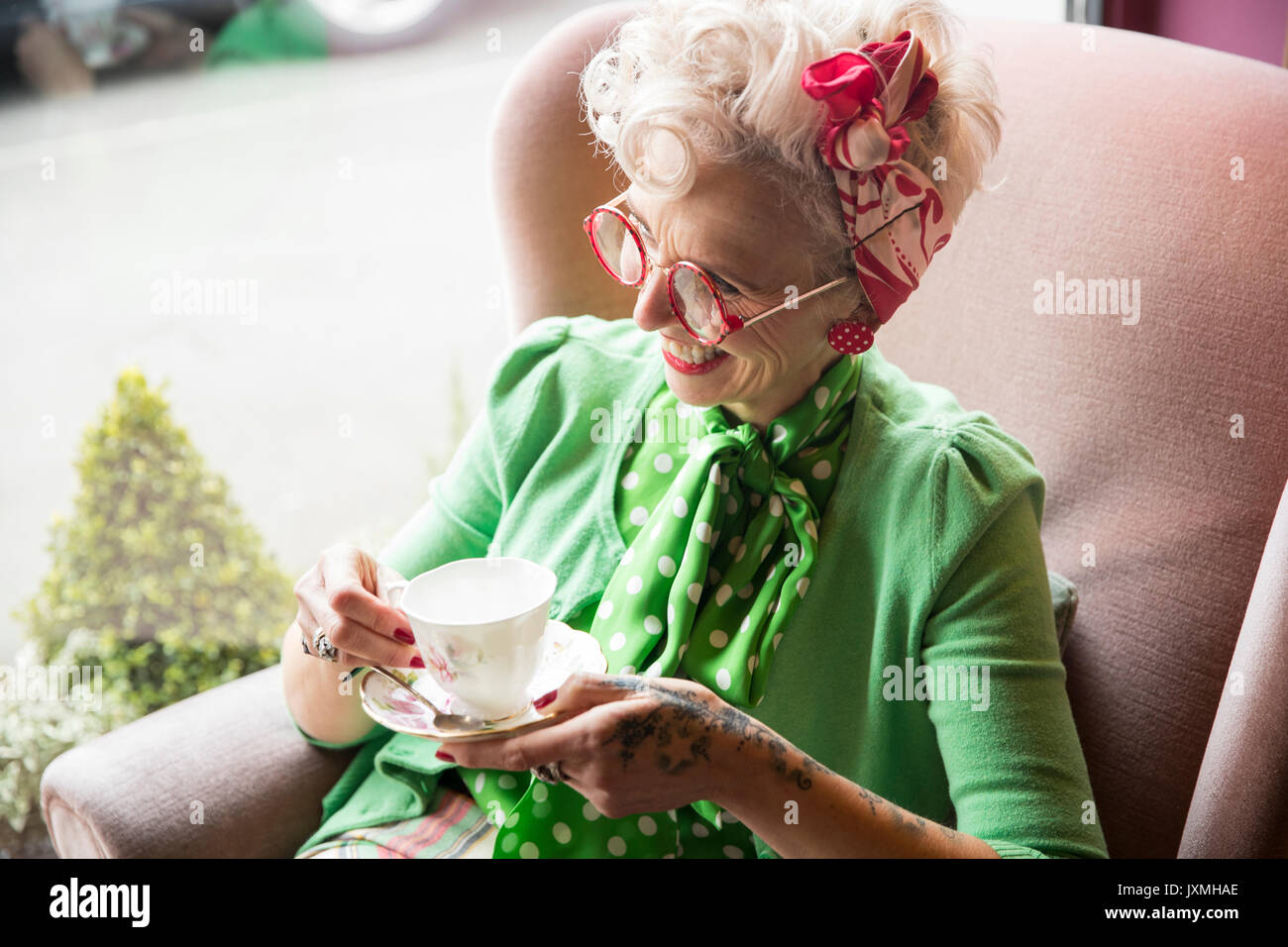 Heureux quirky vintage mature woman holding tasse et soucoupe à thé Banque D'Images