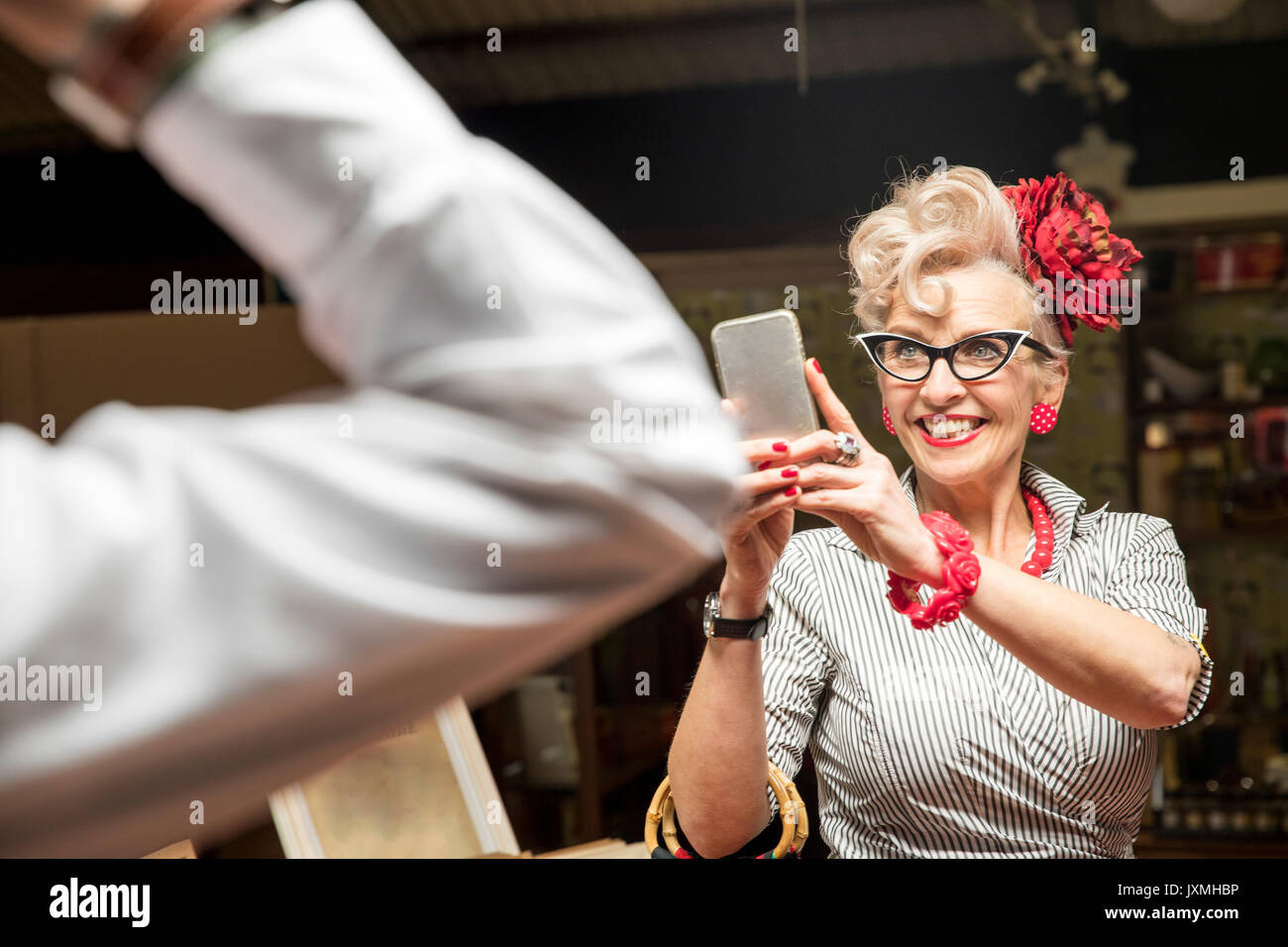 Quirky vintage woman photographing boyfriend dans antiquités emporium Banque D'Images