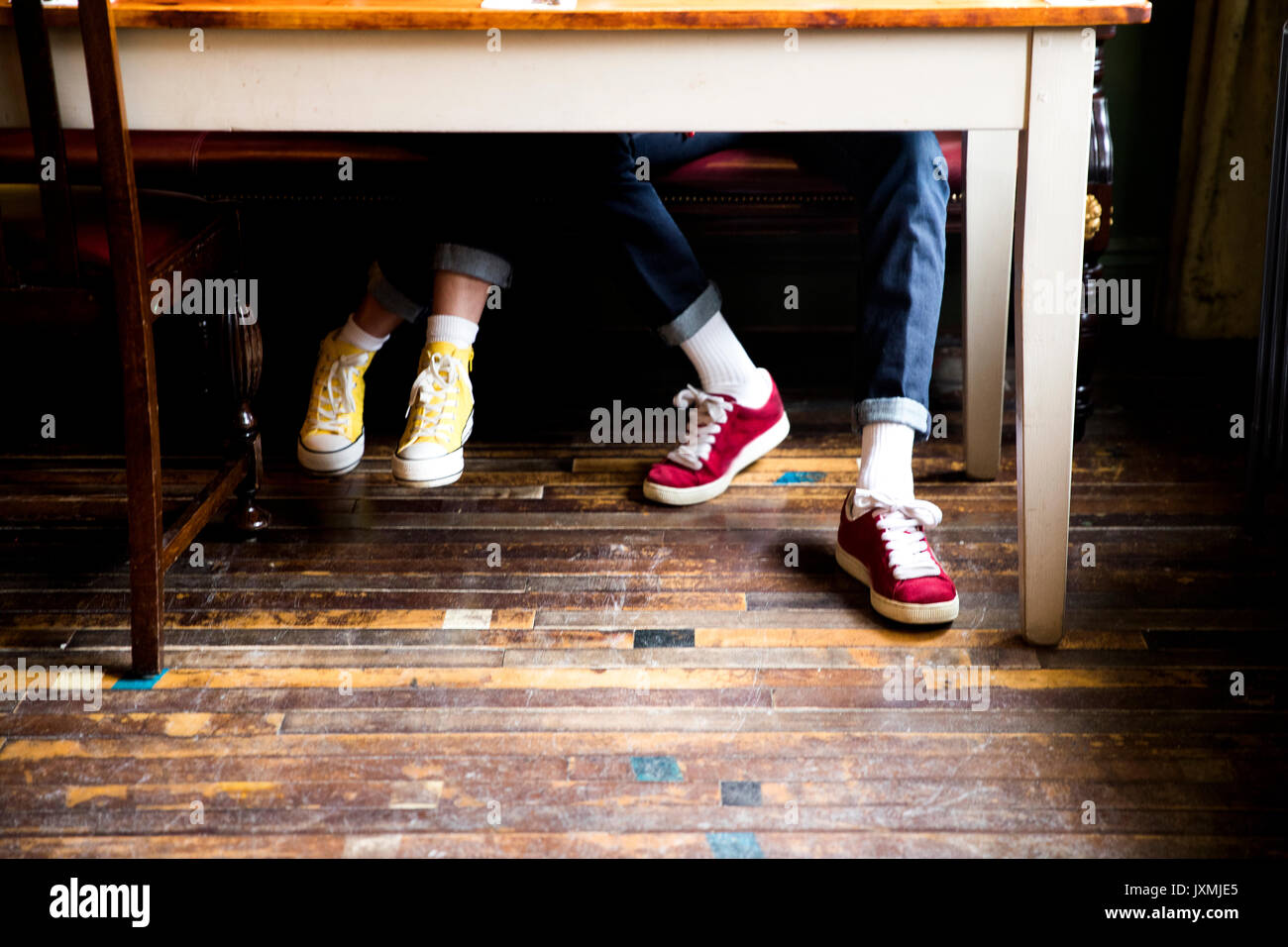 Les jeans et les chaussures portés par couple sitting at table Banque D'Images