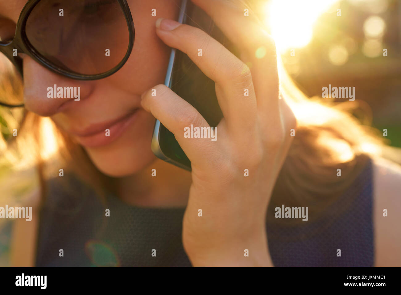 Beauty woman in sunglasses conversation sur le smartphone en marchant dans la rue au coucher du soleil, Close up Banque D'Images