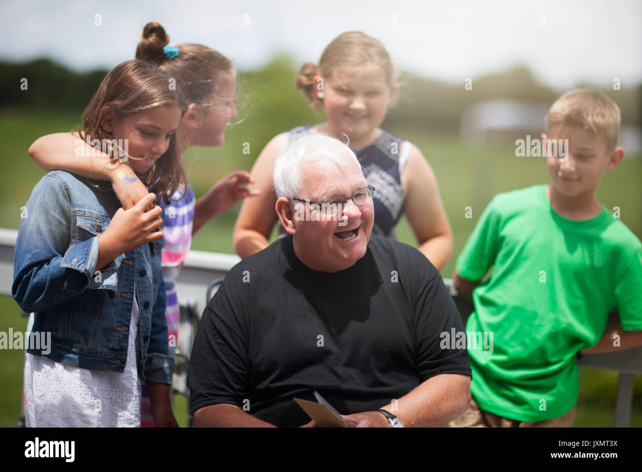 Grand-père entouré de petits-enfants lui donnant carte de souhaits Banque D'Images