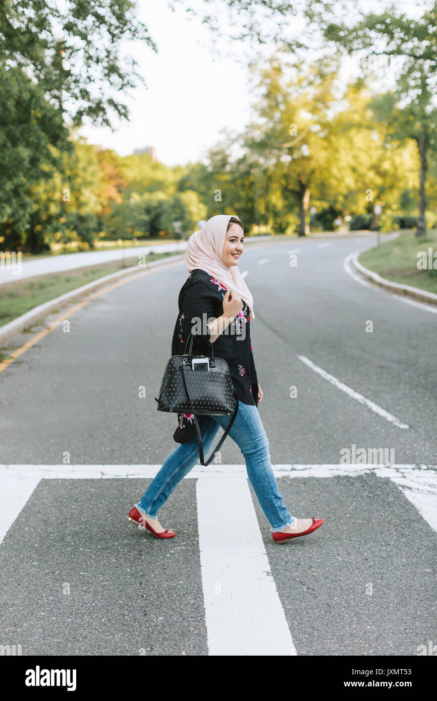 Jeune femme portant le hijab crossing road Banque D'Images