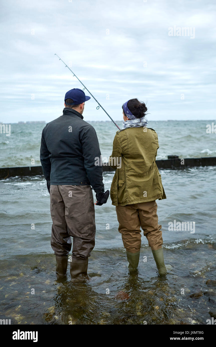 Vue arrière du jeune homme à la cheville dans l'eau pêche en mer petite amie d'enseignement Banque D'Images