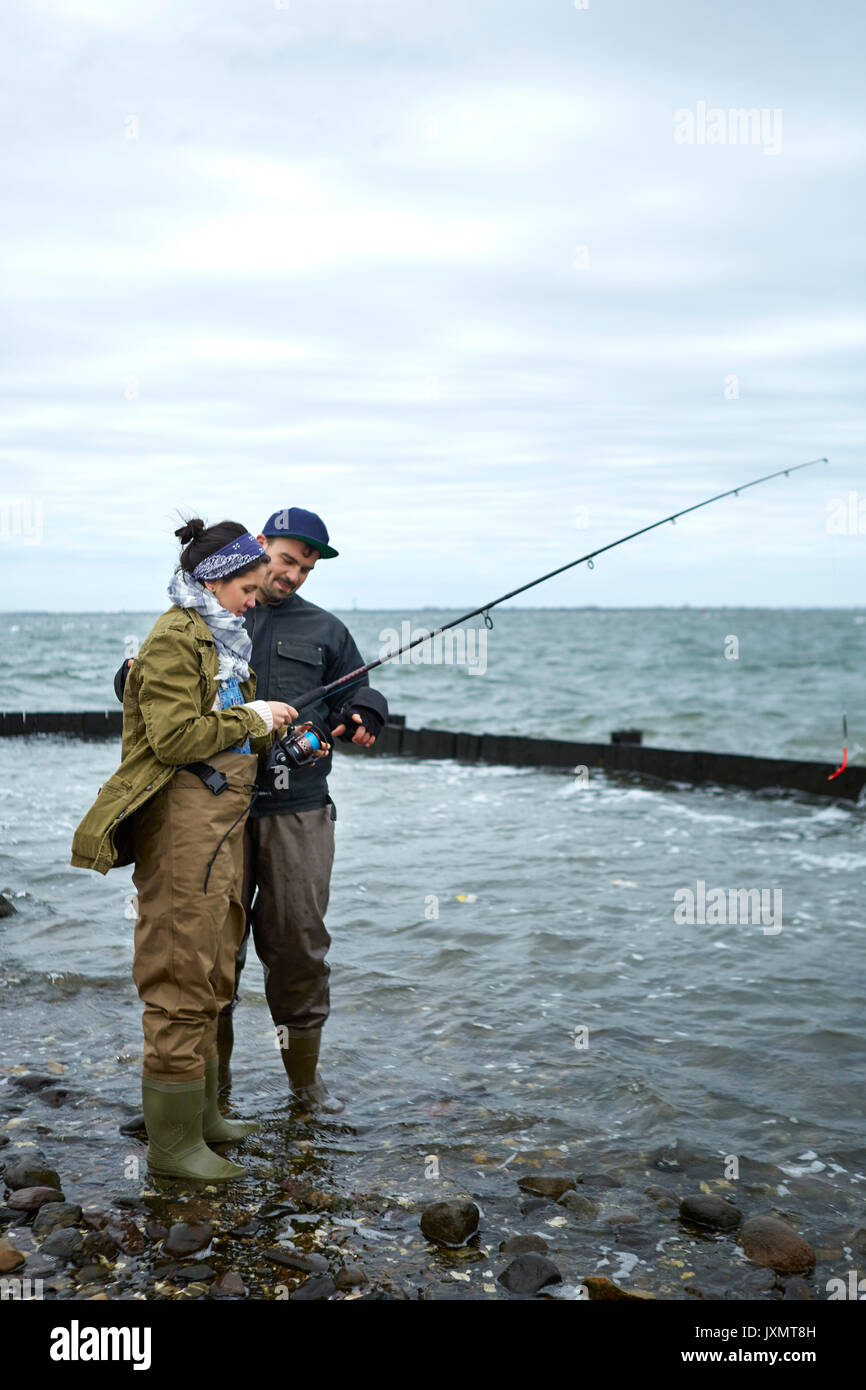 Jeune homme à la cheville dans l'eau pêche en mer petite amie d'enseignement Banque D'Images