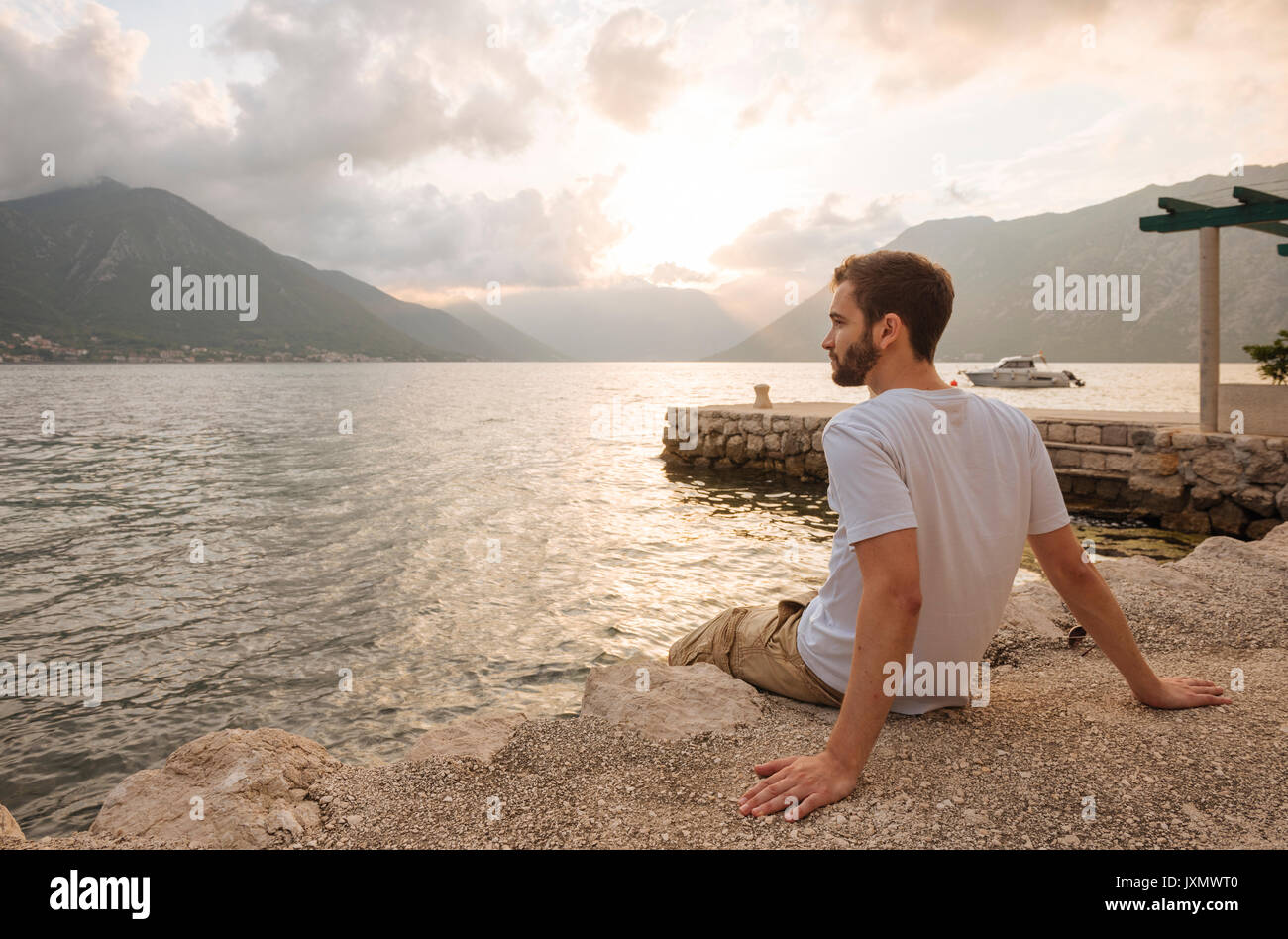 Jeune homme assis par l'eau à l'écart, Kotor, Monténégro, Europe Banque D'Images