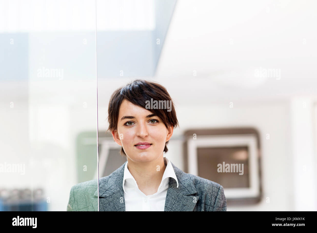 Portrait of young female sales manager par la porte de verre en magasin de meubles de bureau Banque D'Images