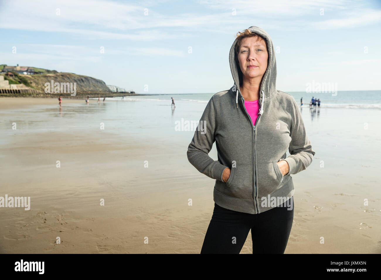 Woman on beach en haut à capuchon, Folkestone, Royaume-Uni Banque D'Images