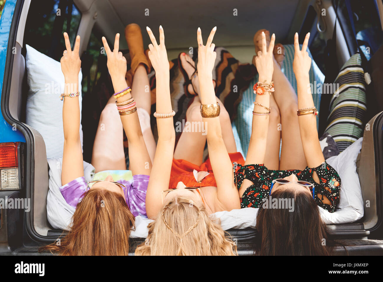 Trois jeunes femmes se trouvant sur le dos de voitures de fabrication des bottes peace sign Banque D'Images