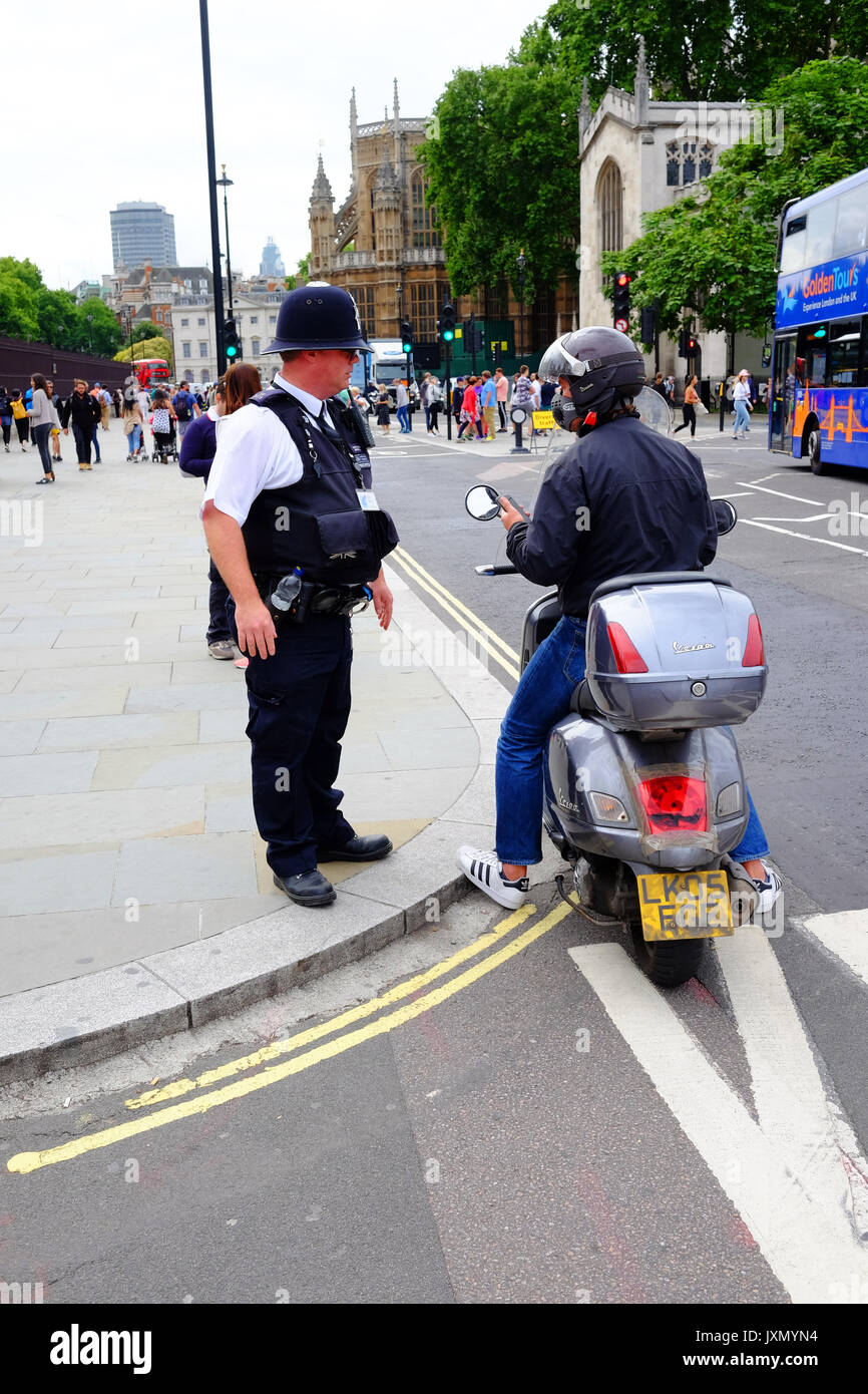 Un policier en service aux portes des chambres du Parliamrnt à Londres, obtient un cyclomoteur stationné rider pour déplacer sur Banque D'Images