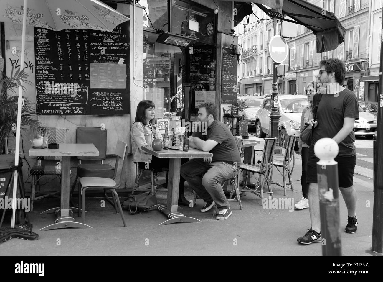 Un couple assis à une table de la chaussée à l'extérieur d'un café dans une banlieue de Paris Banque D'Images