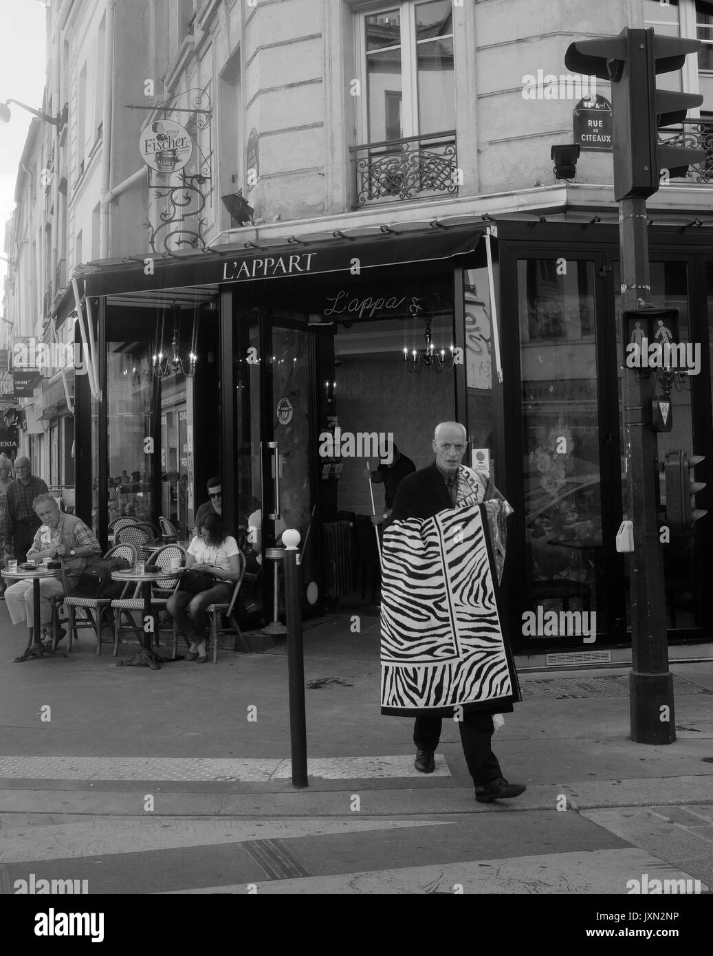 Un vieil homme tente de vendre des tapis sur les rues d'une banlieue de Paris Banque D'Images