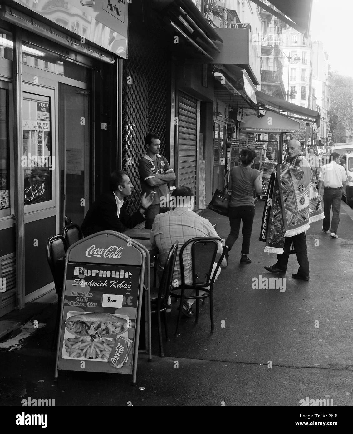 Un vieil homme tente de vendre des tapis sur les rues d'une banlieue de Paris Banque D'Images