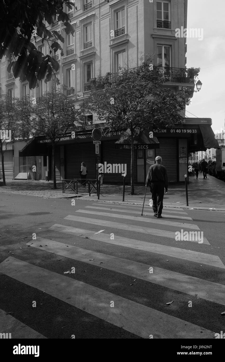 Un vieil homme traverse une rue déserte dans une banlieue de Paris Banque D'Images