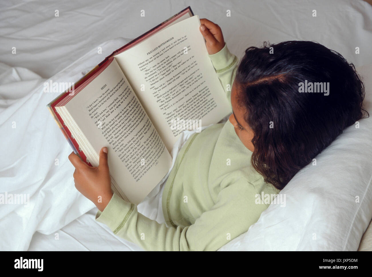 Jeune Fille 7-10 ans reading book in bed Africain/Caucasian © Myrleen Pearson Banque D'Images