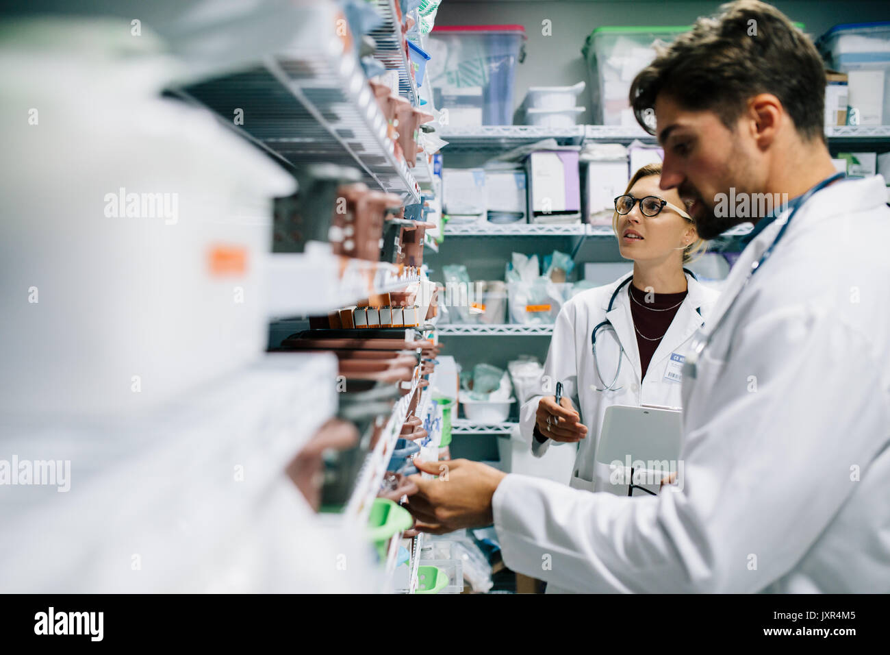 Deux pharmacien travaillant en pharmacie. Les hommes et les femmes contrôle de l'inventaire des médicaments les pharmaciens à la pharmacie de l'hôpital. Banque D'Images