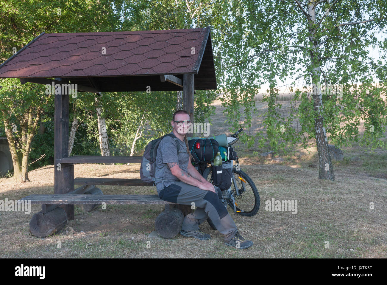 Biker assis sur un banc dans gazepo. Équipements de camping est monté sur le vélo. Banque D'Images