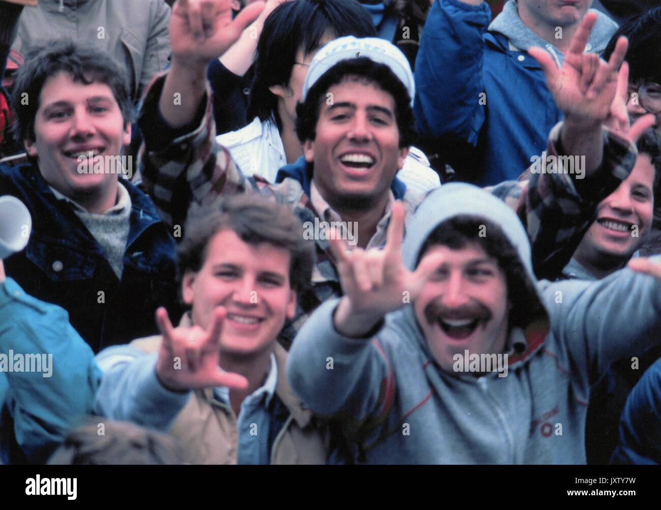 La vie étudiante coup franc, les amateurs de sports dans les gradins à la recherche dans l'appareil photo et les feux de signalisation à main, 1987. Banque D'Images