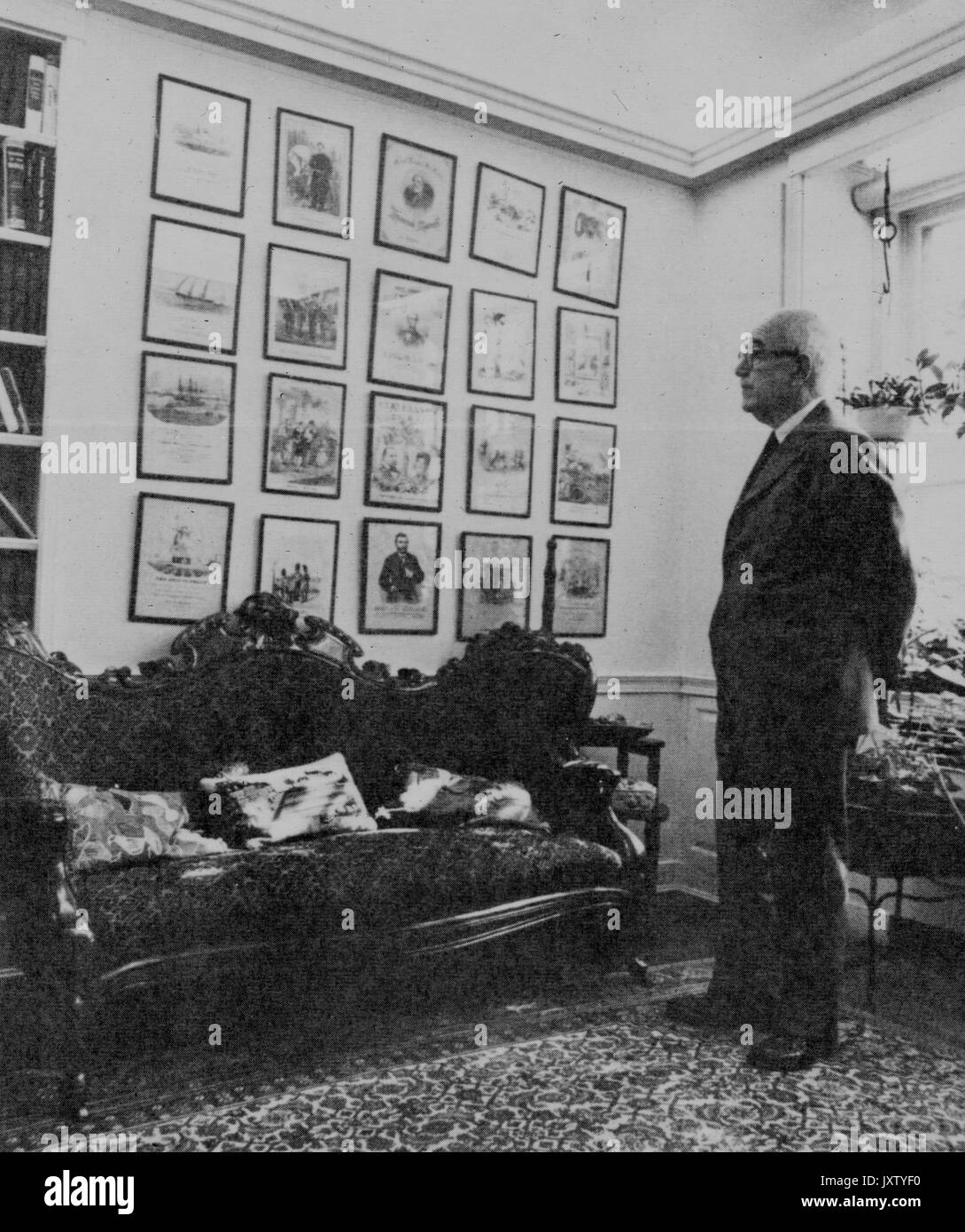 Lester s Levy, photographie candide, Levy, debout devant un mur de photos ou de musique en feuilles, couvre 1978. Banque D'Images