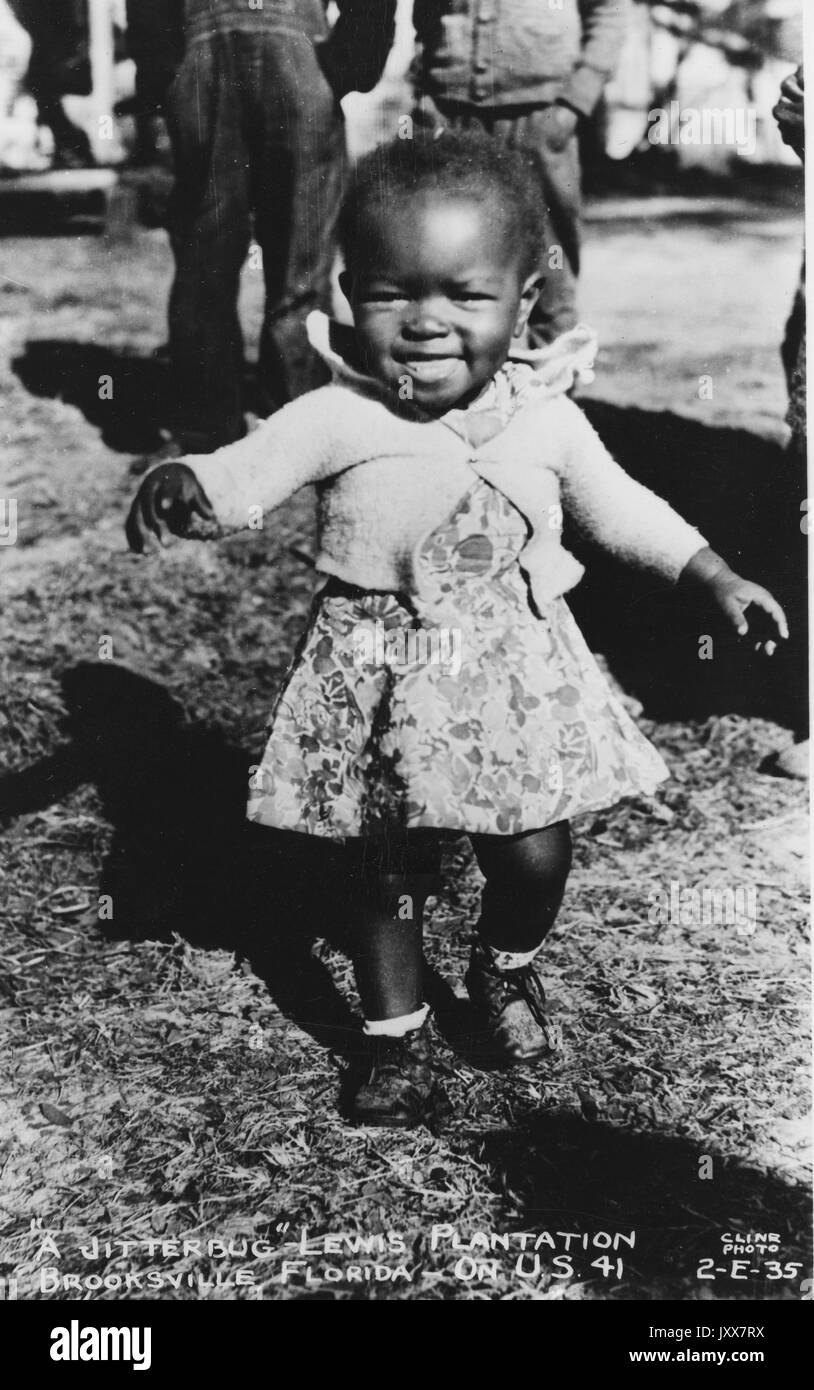 Une jeune fille afro-américaine vêque d'une robe fleurie et d'un chandail souriant et courant dehors sur la plantation Lewis à Brooksville, Floride, 1940. Banque D'Images