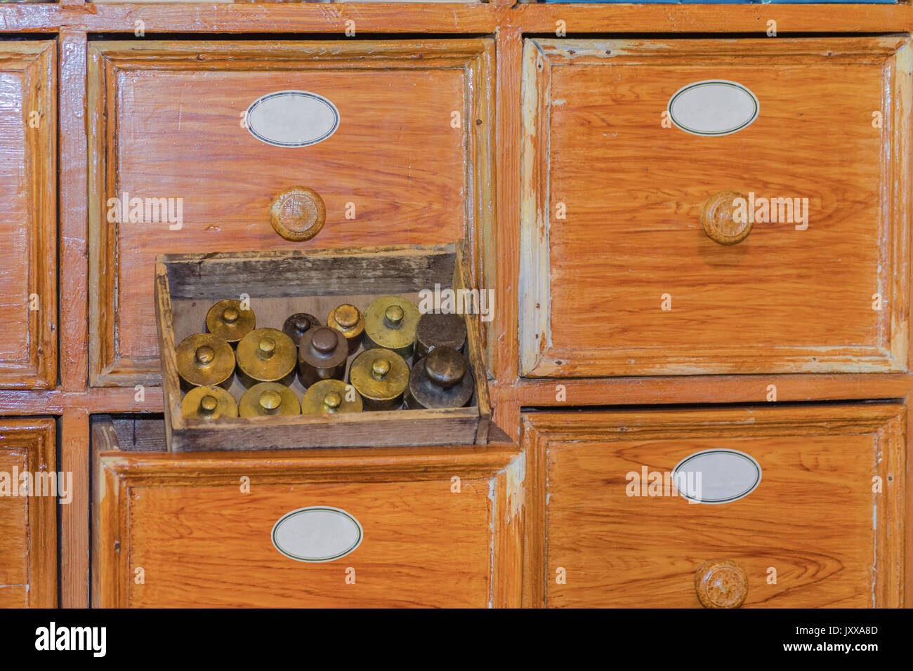 Gros plan d'une armoire à tiroirs de pharmacie très ancienne avec de petits poids en laiton Banque D'Images