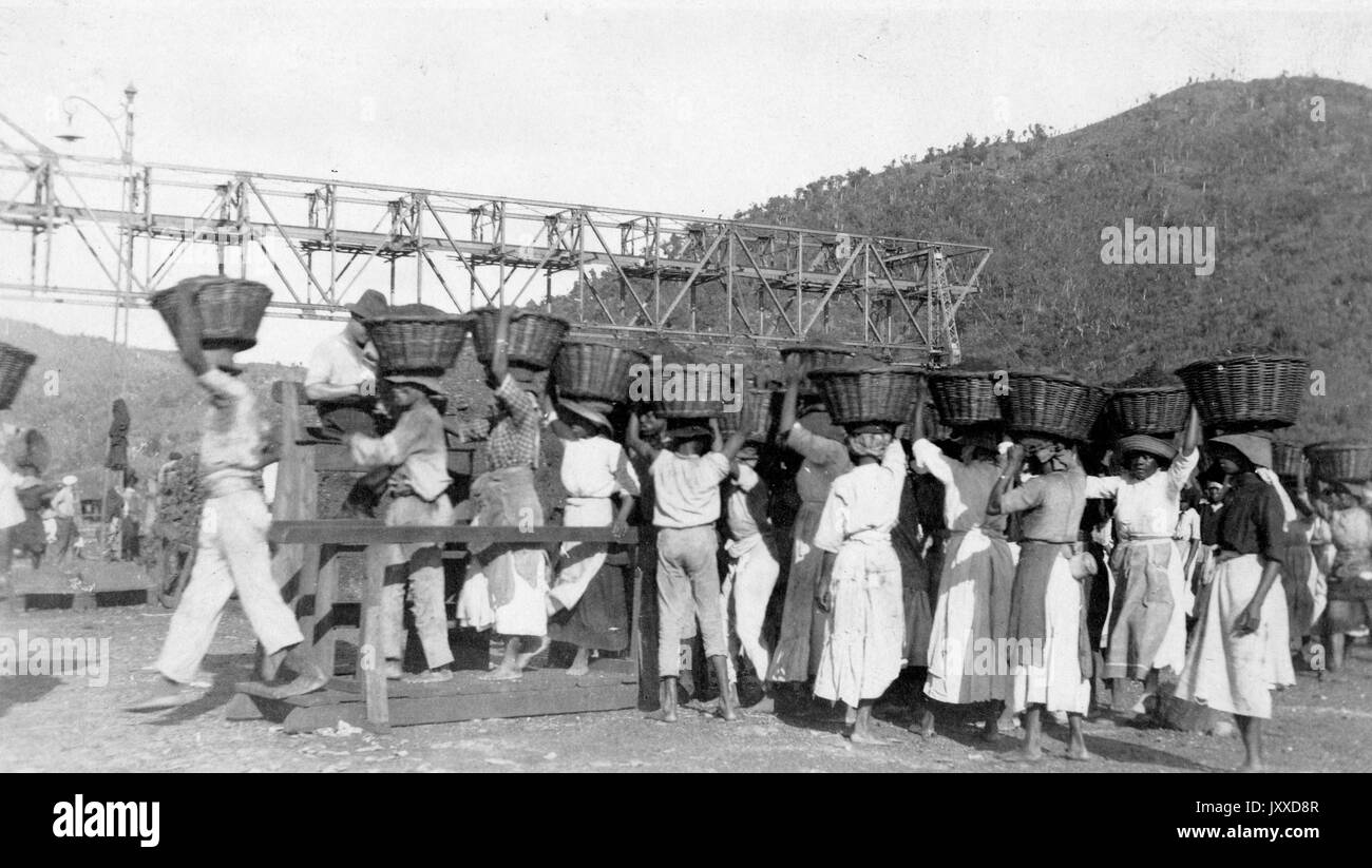 Un grand groupe de travailleurs afro-américains se tient à l'extérieur portant des paniers en osier sur leur tête, 1915. Banque D'Images