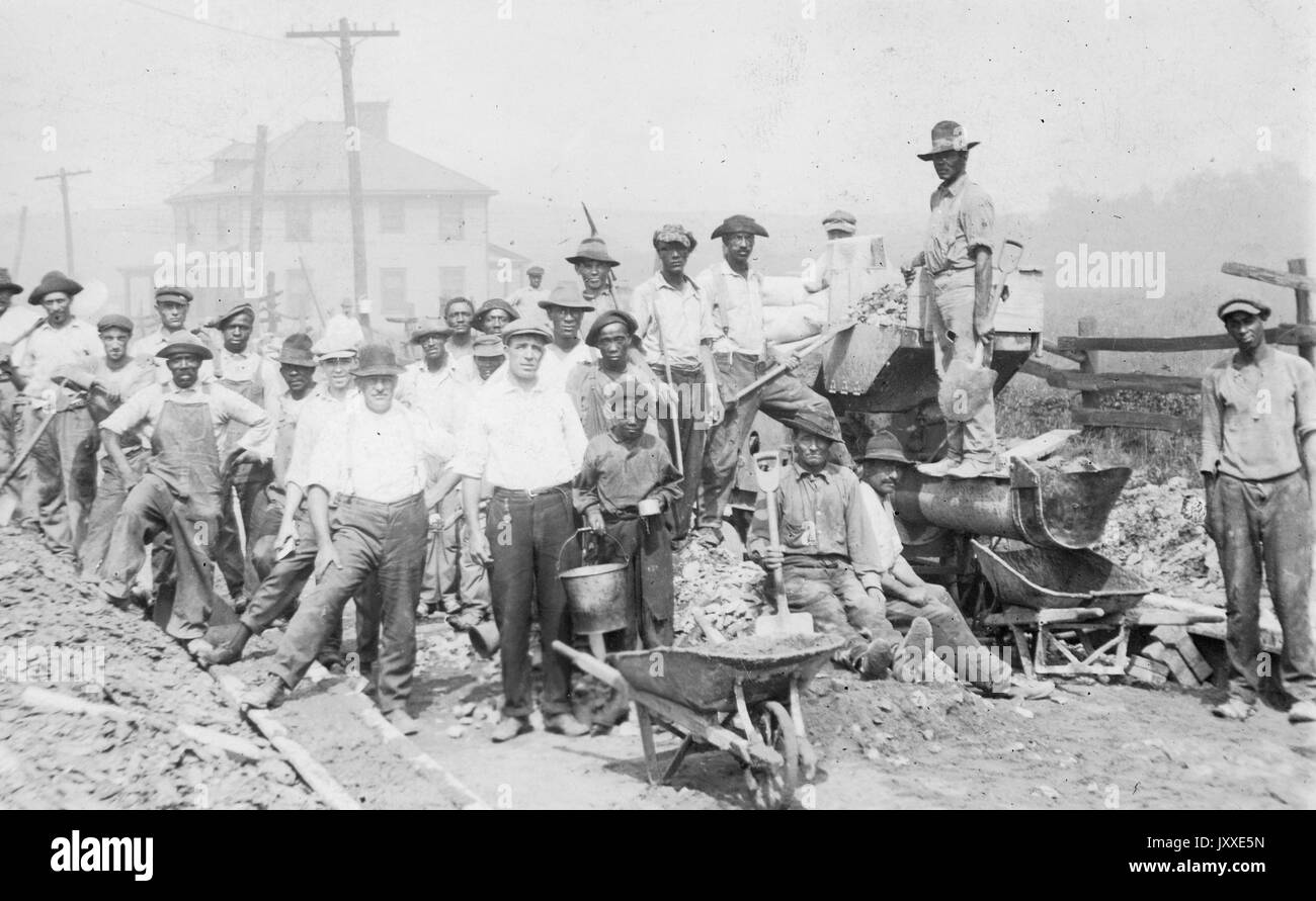 Groupe d'hommes, pour la plupart africains-américains, avec l'équipement, y compris les seaux et les pelles, brouettes, à l'extérieur sur un lieu de travail, 1914. Banque D'Images