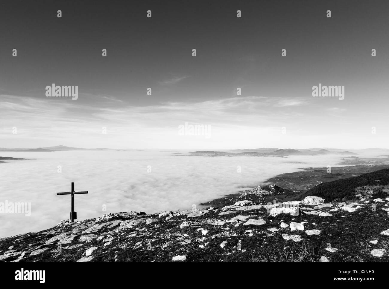 Une croix en bois sur le dessus de la montagne Subasio, avec une mer de brume au-dessous et à Assise (Ombrie) ville en arrière-plan Banque D'Images
