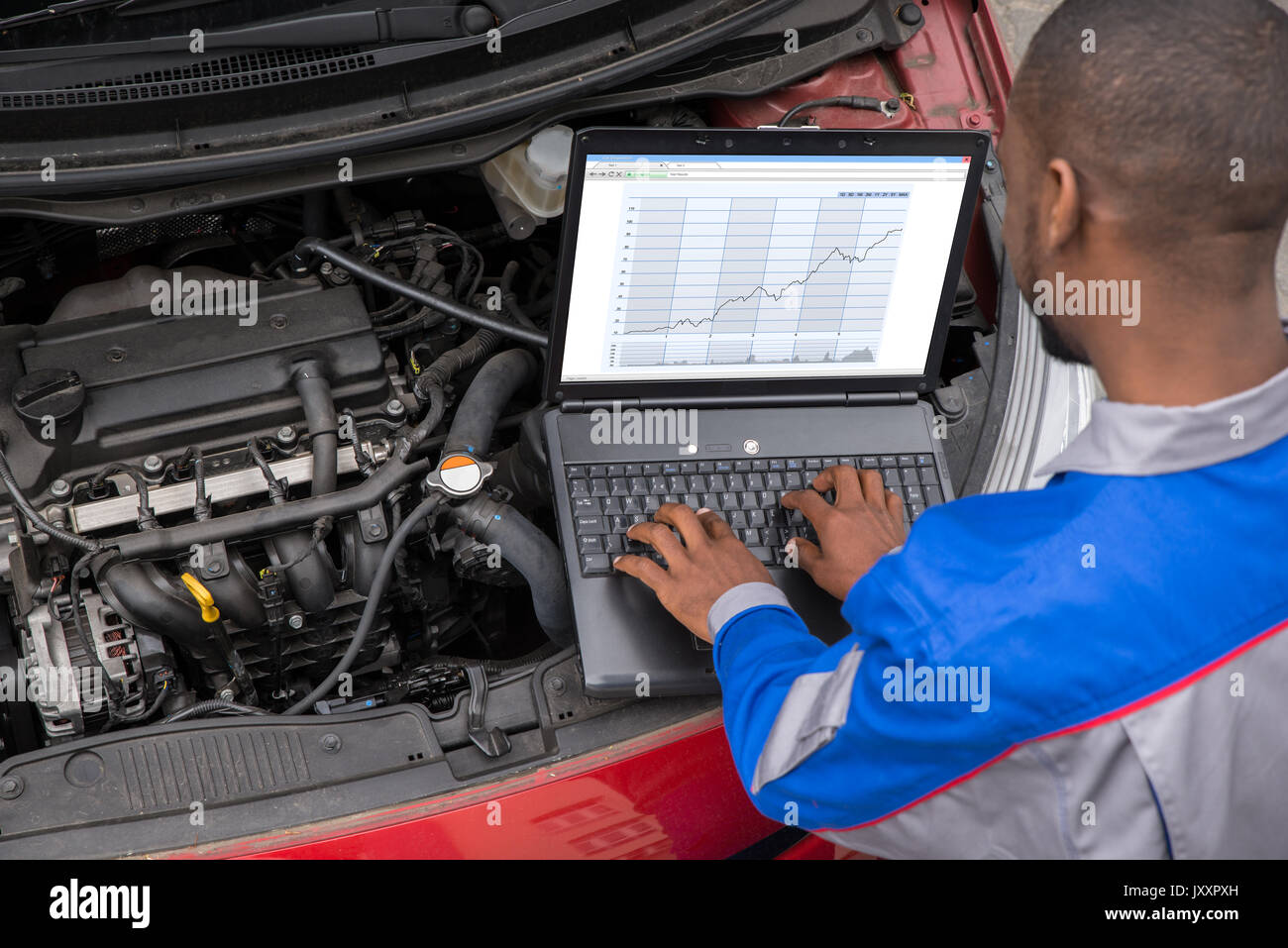 Mécanicien de jeunes hommes à l'aide d'ordinateur portable lors de l'examen du moteur de voiture Banque D'Images