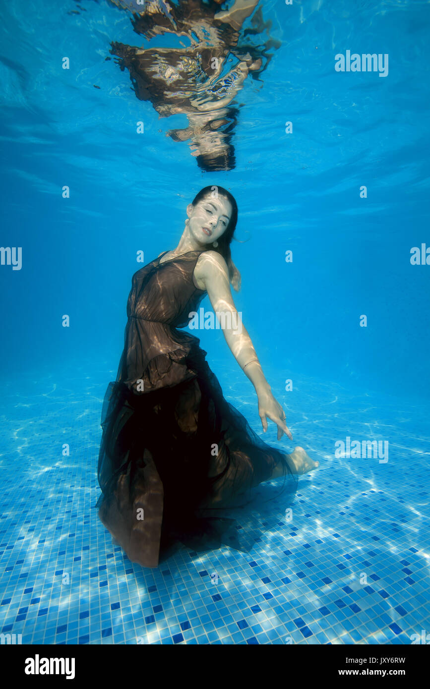 Young Beautiful woman in dress posing sous l'eau dans la piscine Banque D'Images