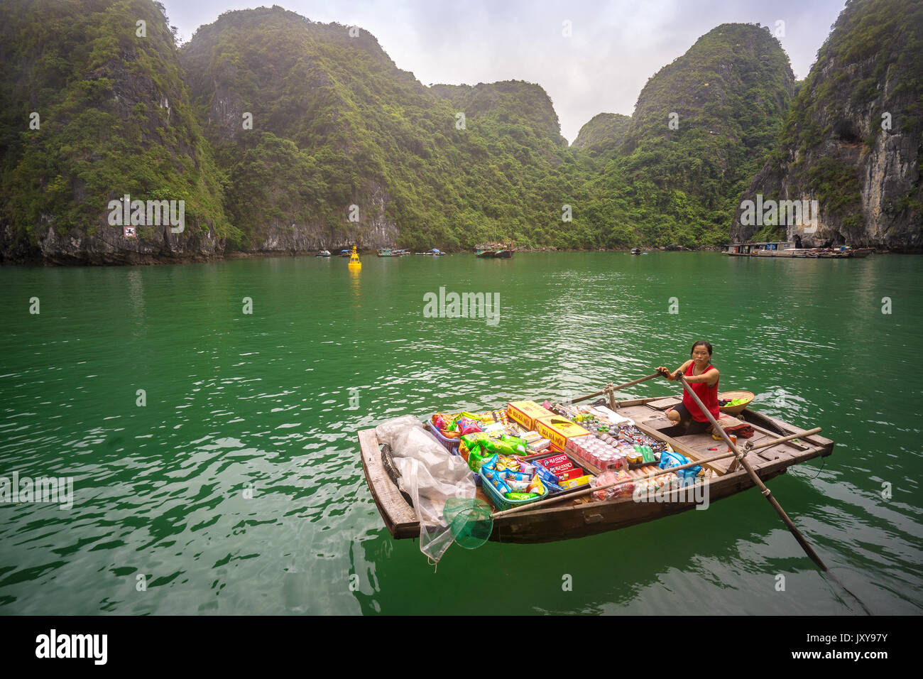 Bateau vietnamien traditionnel vendeur de vendre des produits sur un bateau dans la baie d'Halong, Vietnam Banque D'Images