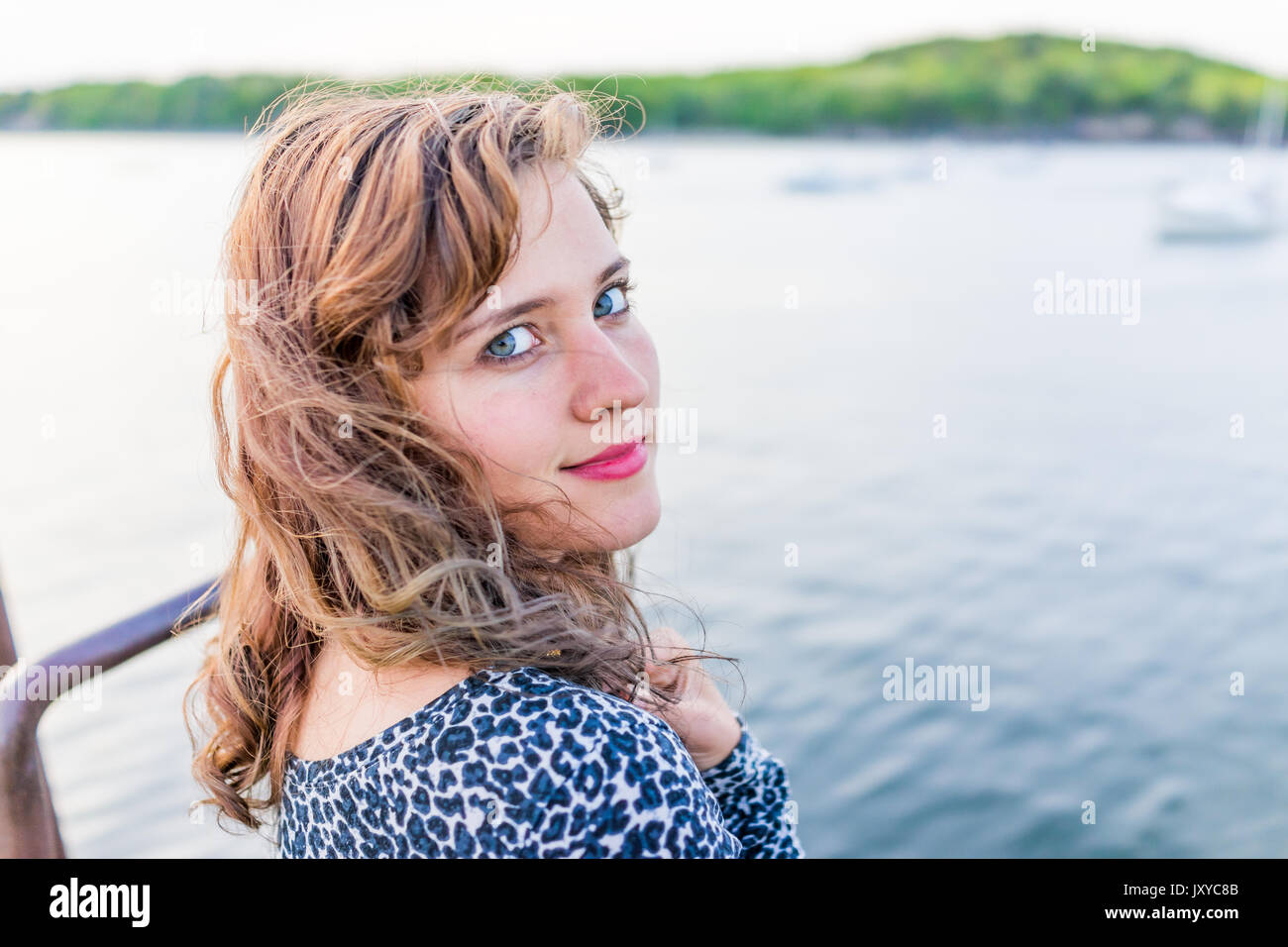 Young happy smiling woman sitting on edge of dock à Bar Harbor, Maine looking over shoulder Banque D'Images