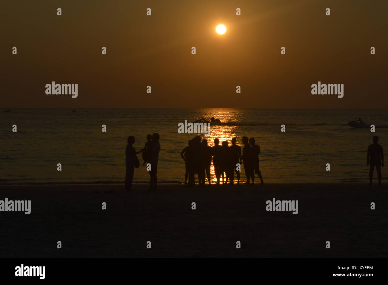 Un groupe de personnes à la plage avant le coucher du soleil Banque D'Images